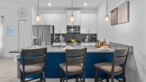 A modern kitchen with a central island, white cabinetry, and pendant lighting. - Gorgeous 5bed TH Close to Disney Water Park (Davenport)