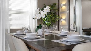 A dining table set with white plates, bowls, and wine glasses, flanked by chairs. - Chic 5bed Home Close to Disney Parks (Davenport)