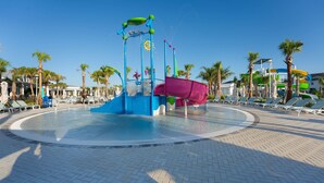 A water park with a central water feature, palm trees, and lounge chairs.