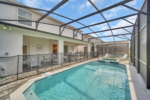 An indoor swimming pool with a glass ceiling, surrounded by lounge chairs and a fenced patio area. - Chic 10br Retreat With Themed Rooms Pool (Clermont)