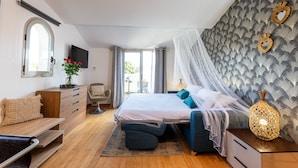 Een slaapkamer met een bed, een dressoir, een stoel, een televisie en uitzicht op het omliggende landschap.