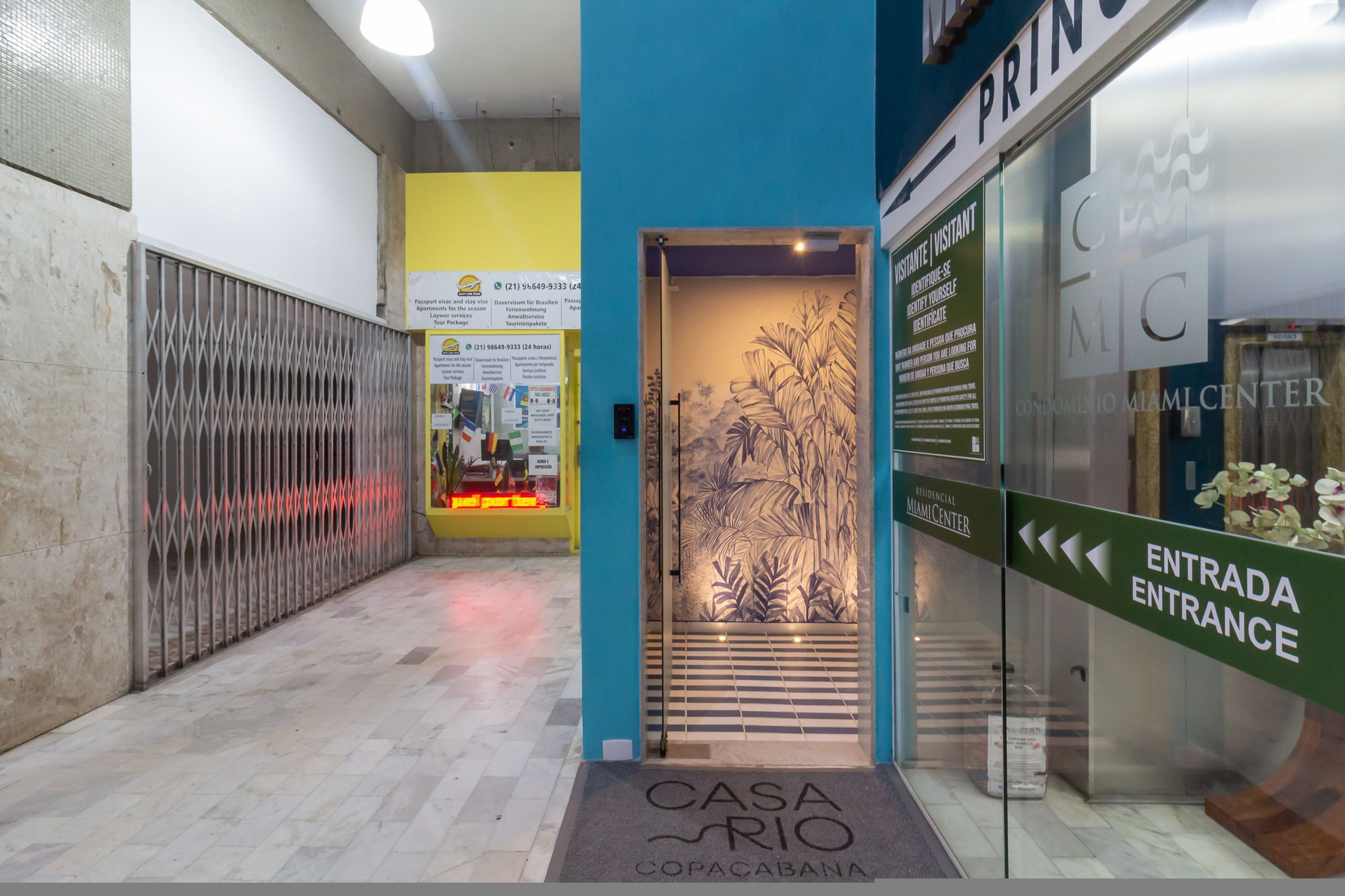 A hotel entrance with a blue wall, a metal gate, and a sign for 'Casa Rio Copacabana'.