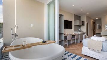 A modern bathroom with a large bathtub, a wooden tray, and a glass of water.