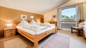 Une chambre à coucher avec un lit en bois, des tables de chevet, une commode et une fenêtre avec des rideaux.