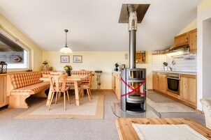 Una cocina acogedora con un estufa de leña central, muebles de madera y una ventana con vistas al jardín.