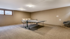 Una habitación con mesa de ping pong, sofá y mecedora.