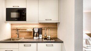 Una cocina moderna con microondas, cafetera y utensilios en la encimera.