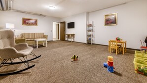 Una sala de estar con sofá, sillón mecedora, una mesita y estantería.