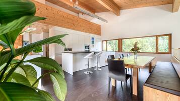 A modern kitchen with white cabinets, a wooden ceiling, and a large window.
