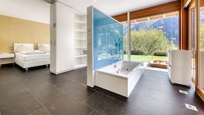 Een moderne badkamer met een bad, een douchegedeelte en een douchecabine met glazen wanden.