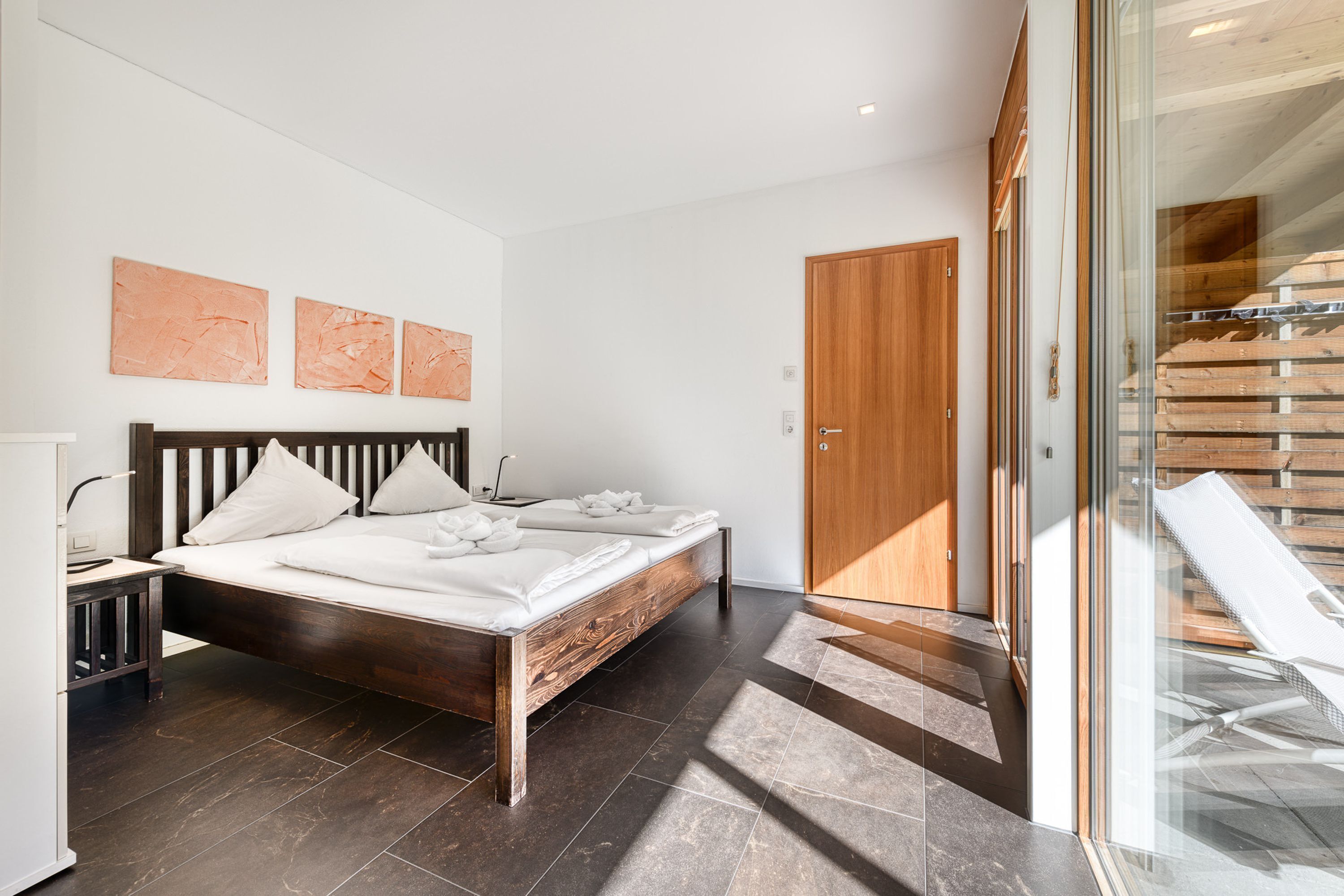 Un dormitorio moderno con una cama grande, una mesita de noche y un armario de madera.