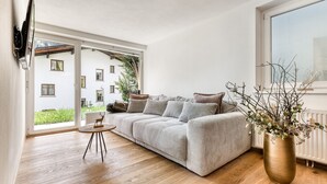Un salon moderne avec un canapé, une table ronde et une grande fenêtre.