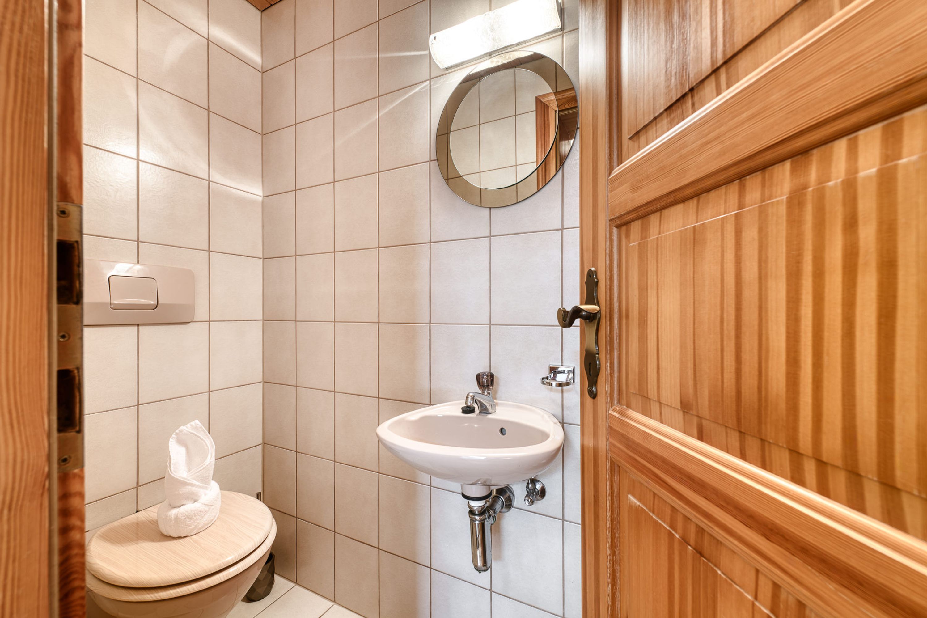 A small bathroom with a toilet, sink, and mirror.