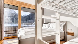 Un intérieur moderne comprenant un lit, un petit bureau et une fenêtre donnant sur les montagnes.