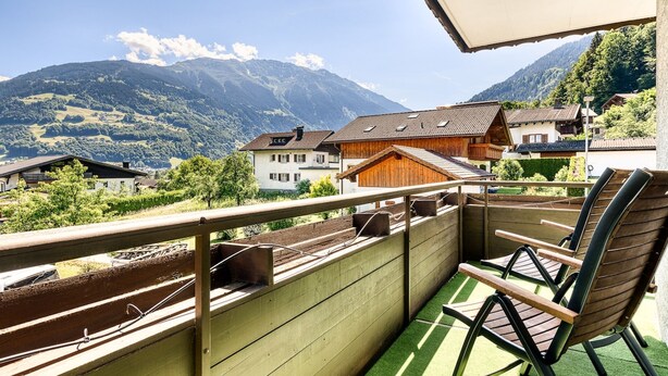 A balcony with a view of a mountain, wooden buildings, and a chair. - Appartement Schruns - M Ser-apartments (Tschagguns)