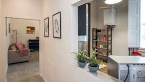 A modern kitchen with a white countertop, two potted plants, and a built-in refrigerator.