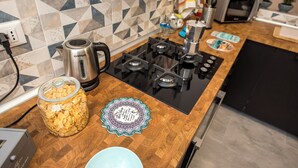 A kitchen with a modern stove, a kettle, a jar of cereal, and a decorative plate.