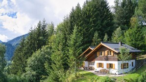 A cabin with a wooden exterior, surrounded by dense forest and mountains. - Waldh tte Panorama Tschengla (Buerserberg)