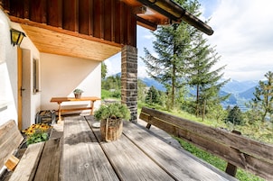 Terraza de madera con banca y mesa, con vista a un paisaje montañoso.