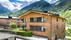 Ein modernes Backsteingebäude mit Balkon, großen Fenstern und Bergblick.