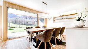 Ein moderner Essbereich mit großem Fenster, Holzboden und Blick auf eine gebirgige Landschaft.