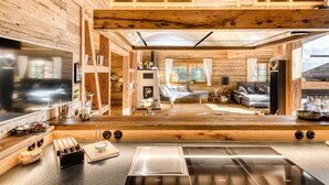 A modern kitchen with a large stove, wooden cabinetry, and a dining area with a table and chairs. - Chalet GM - Penthaus (Brand)