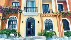 A multi-story building with a central entrance, balconies, and a number '104' visible. - Deluxe 4 br Lucky Villa-Nova Phan Thiet (Tien Thanh)
