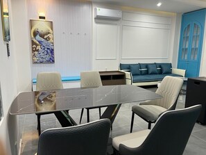 Ein Konferenzraum mit Glastisch, vier Stühlen, einem blauen Sofa und einem Wandbild mit einem Pfau.