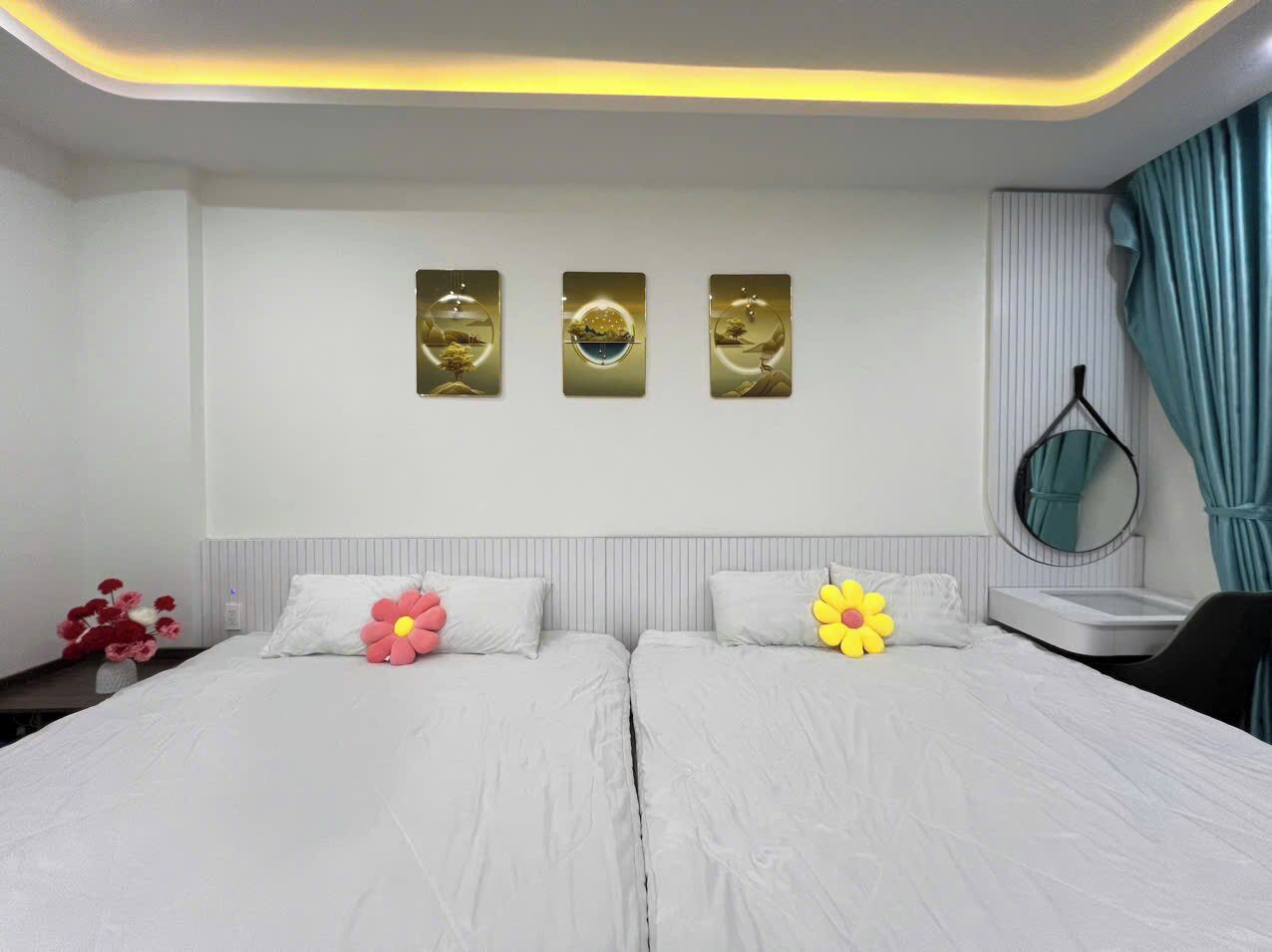 Une chambre d’hôtel avec deux lits, une table de chevet, un miroir et trois œuvres d’art murales.