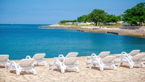 A beachside pool area with white lounge chairs and a clear view of the sea.