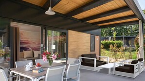 An outdoor patio with white furniture, a dining table, and a flower vase.