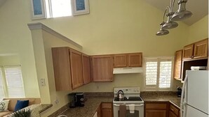 A kitchen with granite countertops, wooden cabinets, a stainless steel sink, and a white refrigerator.