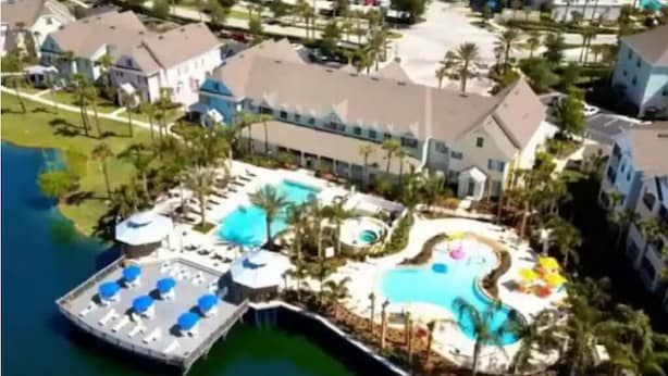 A resort with a large pool, a dock, and a building with multiple balconies.