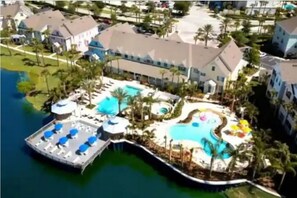 Un resort con una piscina grande, un muelle y un edificio con varios balcones.