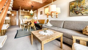 Ein gemütliches Wohnzimmer mit einer Holztreppe, einer Essecke und einem Sofa.