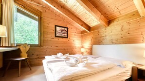 Ein Zimmer in einer Holzhütte mit einem Bett, einem Schreibtisch und einem Stuhl.