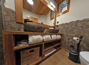 A bathroom with stone walls, wooden shelves, and a mirror. - LA MASIA DEL TAULAT CHAMBRES D  HOTES (Llo)