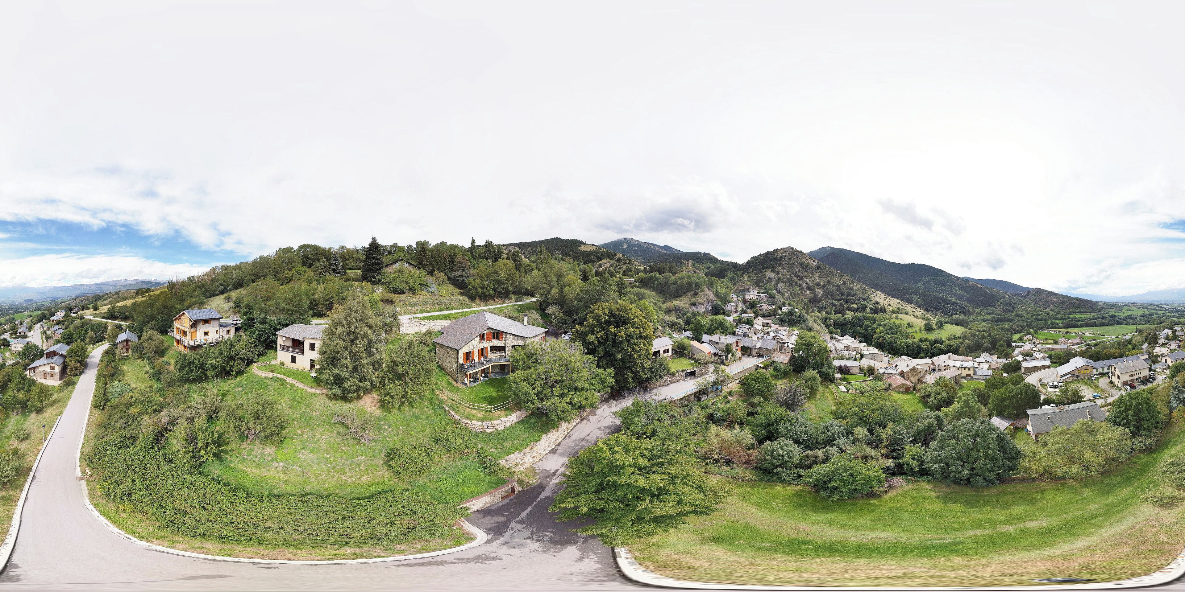 Un barrio residencial con casas en una ladera, una carretera sinuosa y vistas a montañas distantes.