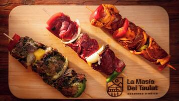 Cuatro brochetas de carne sobre una tabla de madera.