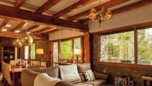 A cozy living room with a wooden ceiling, stone walls, a large window, and a comfortable sofa. - LA MASIA DEL TAULAT CHAMBRES D  HOTES (Llo)