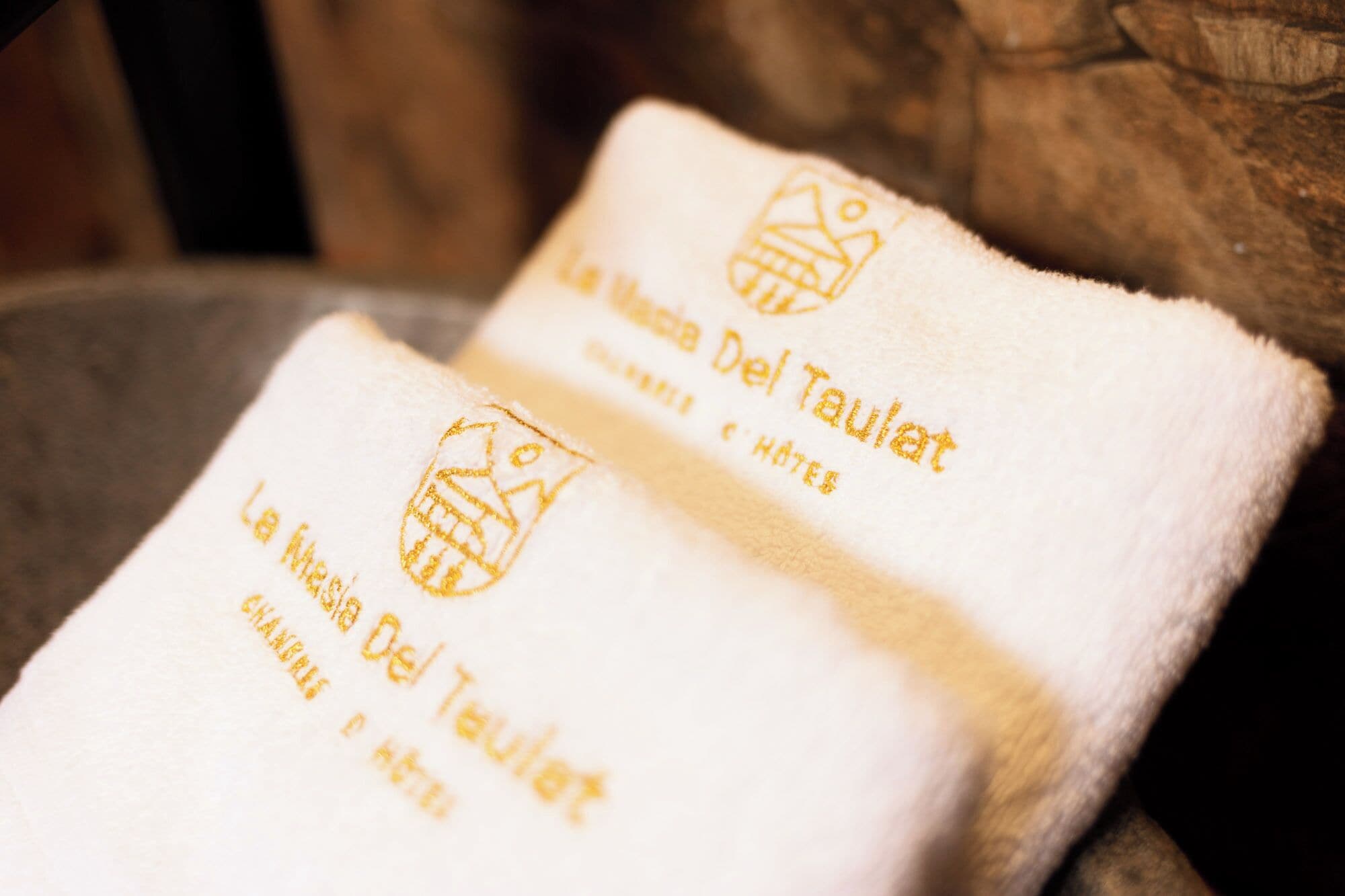 Two white towels with embroidered text and logos, placed on a wooden surface.
