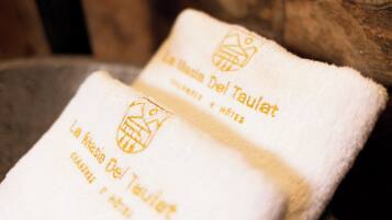 Two white towels with embroidered text and logos, placed on a wooden surface.
