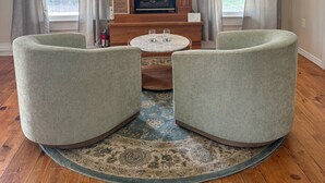 A living room with a fireplace, two armchairs, a coffee table, and a rug. - Carriage House at the Mansion on Market Street (Hermann)