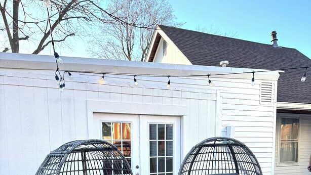 Two black wire-framed chairs with grey cushions in front of a white house with a grey roof. - Carriage House at the Mansion on Market Street (Hermann)