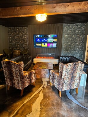 Un salon moderne avec une cheminée, des meubles en cuir et un grand téléviseur à écran plat fixé au mur.