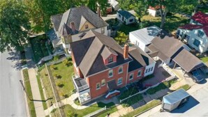 A multi-story house with a prominent gabled roof, a visible chimney, and a front porch. - Carriage House at the Mansion on Market Street (Hermann)