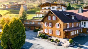 A multi-story hotel with a traditional Alpine architectural style, featuring a prominent balcony and a well-maintained garden area. - Ferienwohnung Zentral mit Panorama-sonnenterrasse (Brand)