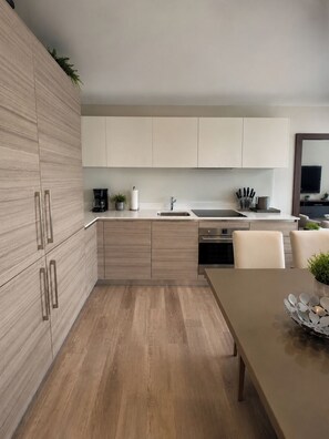 A modern kitchen with wooden cabinets, a sink, a coffee maker, and a dining area with a table and chairs. - Chic 1-bedroom with Partial Ocean View WiFi, AC, in fabulous Hollywood . (Hollywood)