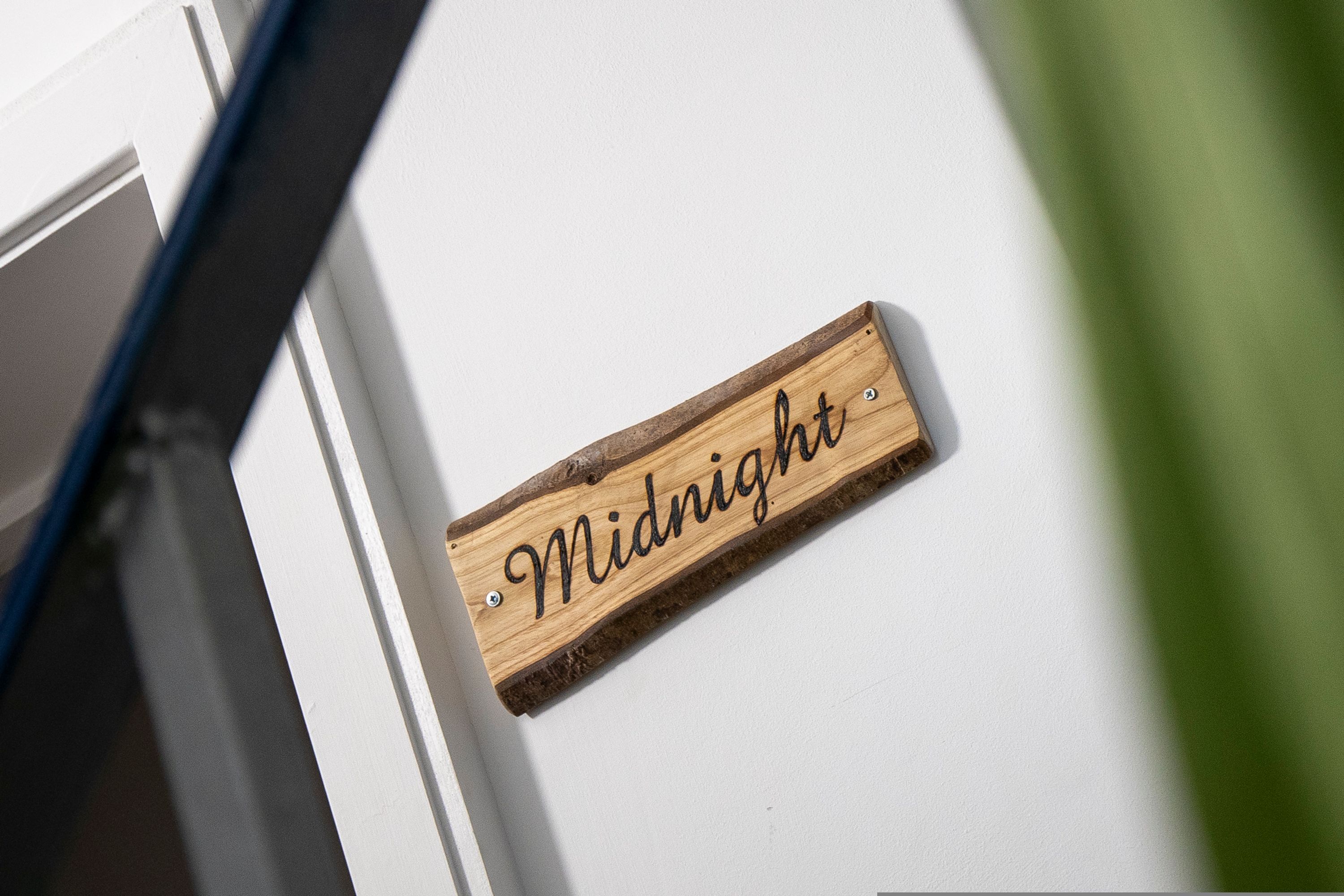 A wooden sign with the word "Midnight" on a white wall.