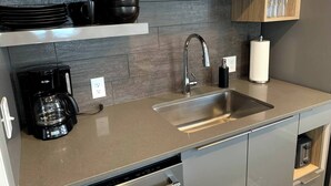 A modern kitchen with a stainless steel sink, a coffee maker, and a dishwasher. - Monthly Luxury Loft - Old Town (Fort Collins)